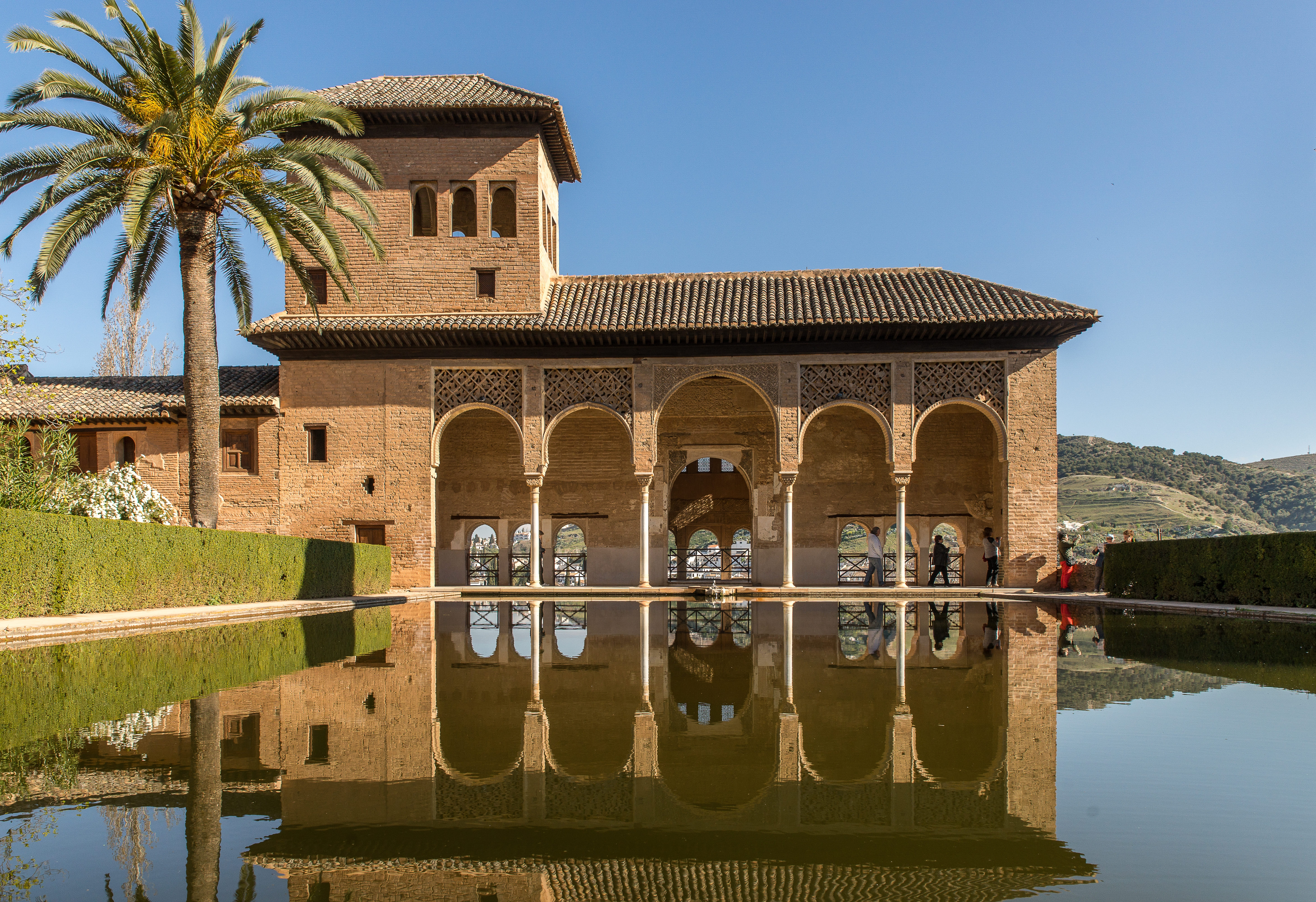 Moorish palace with reflecting pond and palm tree — architectural heritage of Marrakech luxury real estate
