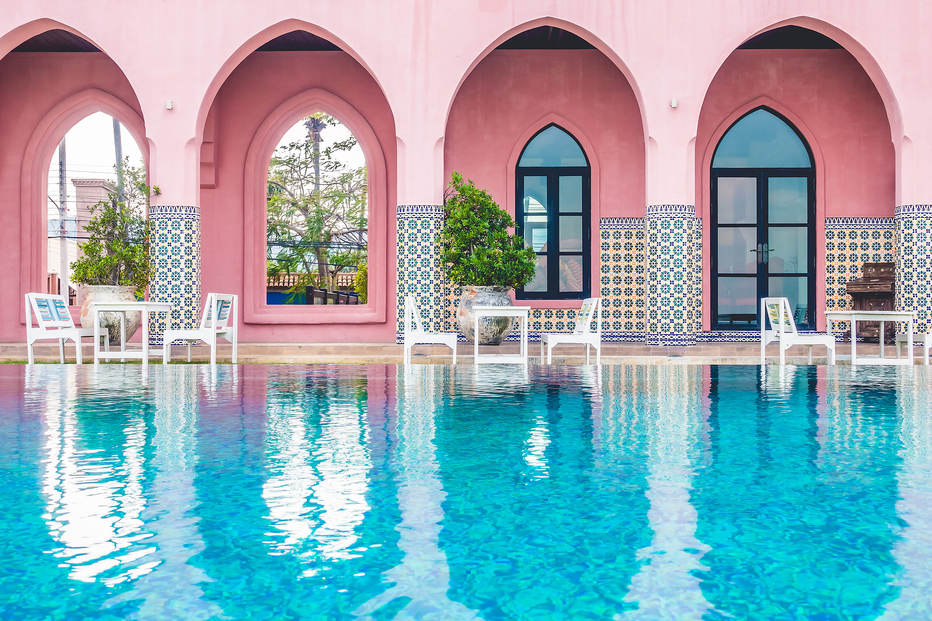 Riad pool with pink Moroccan arches and traditional zellige tilework in Marrakech Medina