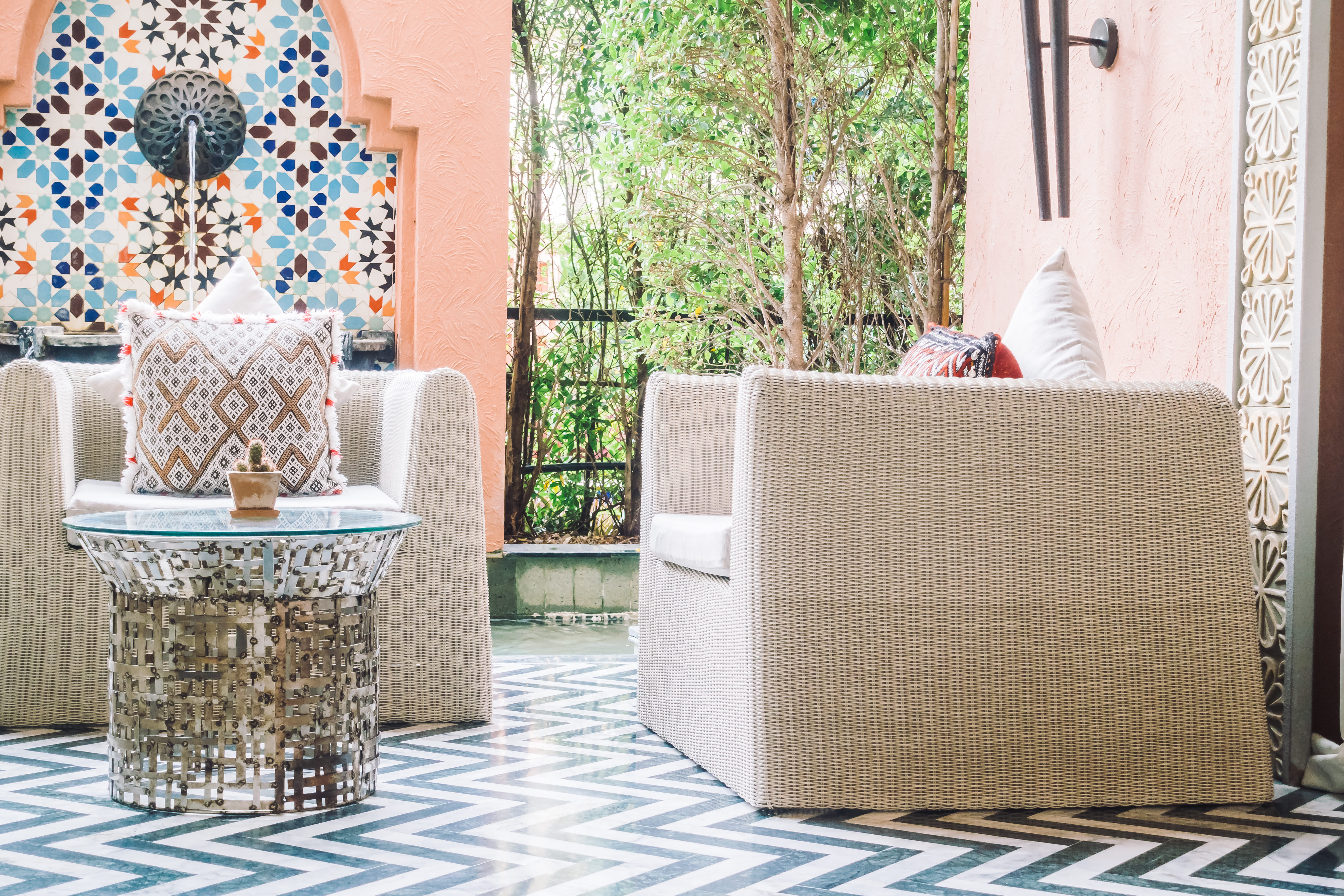 Elegant riad terrace lounge with Moroccan zellige floor and carved plasterwork in Marrakech